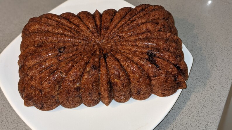 May include: A brown loaf cake with a starburst pattern baked in a fluted loaf pan.