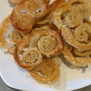 May include: A plate of golden brown palmiers, a French pastry, with a sugary glaze.