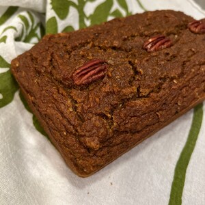May include: A loaf of pecan bread on a white and green patterned tea towel.