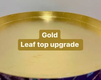 May include: Close-up of a gold leaf top upgrade for a tray or table. The top is smooth and shiny, with a subtle sheen. The text "Gold Leaf top upgrade" is visible in the image.