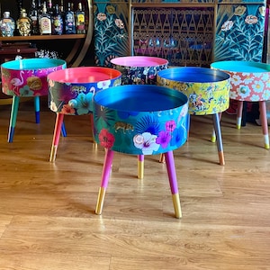 May include: Five colourful side tables with floral and animal prints. The tables have gold legs and are made of wood.
