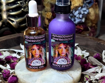 Può includere: Due flaconi di prodotti per il corpo, uno ambrato e uno viola, con etichette raffiguranti il ritratto di una donna. Il flacone ambrato è etichettato "Body Oil", e il flacone viola è etichettato "Body Spray". Entrambi i flaconi riportano la scritta "Aphrodisiac Pheromone".