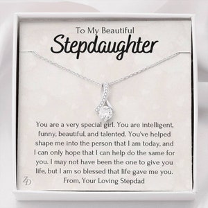 May include: A silver necklace with a small, clear crystal pendant in a box with a message to a stepdaughter. The message reads "To My Beautiful Stepdaughter. You are a very special girl. You are intelligent, funny, beautiful, and talented. You've helped shape me into the person that I am today, and I can only hope that I can help do the same for you. I may not have been the one to give you life, but I am so blessed that life gave me you. From, Your Loving Stepdad."