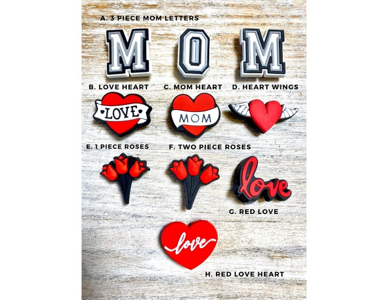 May include: A set of red and white shoe charms with various designs, including the word "MOM", hearts, roses, and the word "love".