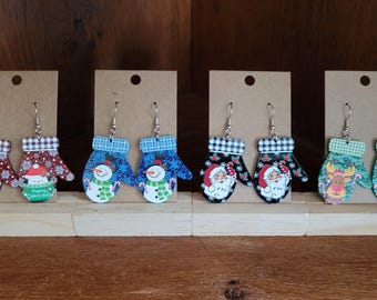 Puede incluir: Ocho pares de pendientes colgantes con temática navideña. Cada par presenta un diseño diferente, incluyendo un muñeco de nieve, Papá Noel y un reno. Los pendientes están hechos de madera y tienen un acabado pintado.