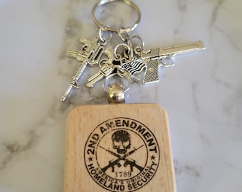 May include: A wooden keychain with a black and white skull and crossbones design. The keychain says "2nd Amendment", "America's Original Homeland Security", and "1789".