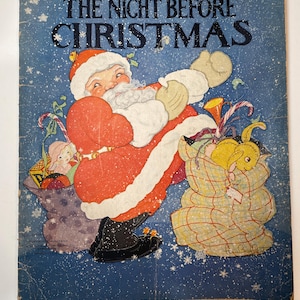May include: A vintage children's book cover featuring a cartoon illustration of Santa Claus carrying a large sack of gifts. The book title is "The Night Before Christmas" and the cover is blue with a white snowflake pattern.
