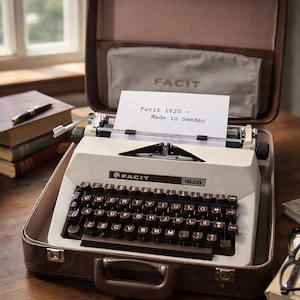 May include: A classic Facit 1620 typewriter in a brown case. The typewriter is cream-coloured with brown keys and the text "Facit 1620 - Made in Sweden" on a sheet of paper. The case is open, showing the typewriter inside.