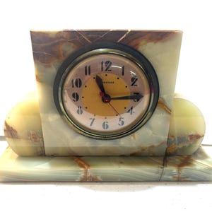 May include: A green marble clock with a white face and black hands. The clock is set on a green marble base with a brown and green marble design.