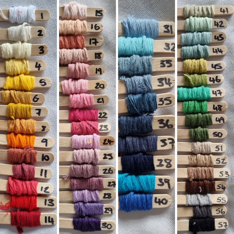 May include: A collection of 57 different colored embroidery floss spools, each wrapped around a wooden stick with a number label. The floss colors range from white to black, with shades of red, orange, yellow, green, blue, and purple.