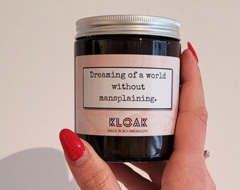 May include: A dark glass jar with a silver lid, held by a hand with red nail polish. The label reads "Dreaming of a world without mansplaining." The jar is from KLOAK, made in Bournemouth.