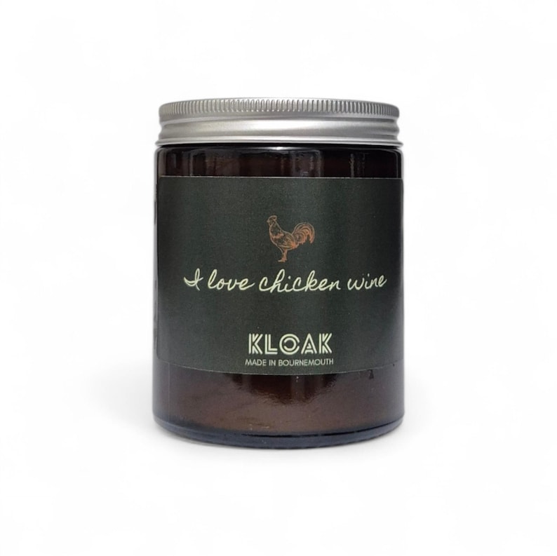 May include: A glass jar with a silver lid and a dark green label. The label features a gold rooster illustration and the text "I love chicken wine" and "KLOAK MADE IN BOURNEMOUTH".