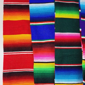 Könnte beinhalten: Drei bunte mexikanische Decken mit gestreiften Mustern in Rot, Blau, Grün, Gelb, Orange, Rosa und Weiß.