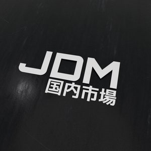 Peut inclure: Autocollant JDM blanc avec le texte "国内市場" en caractères japonais.