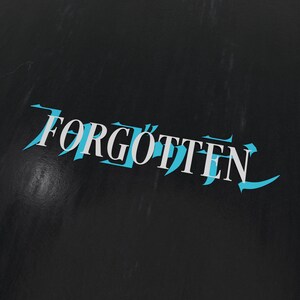 Könnte beinhalten: Das Wort "FORGOTTEN" ist in weißen Buchstaben mit blauer Umrandung auf schwarzem Hintergrund geschrieben.