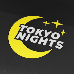 Könnte beinhalten: Ein gelber Halbmond mit drei weißen Sternen und dem Text "TOKYO NIGHTS" in weißen Buchstaben.