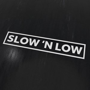 Peut inclure: Un panneau noir et blanc avec le texte "SLOW 'N LOW" en lettres blanches.