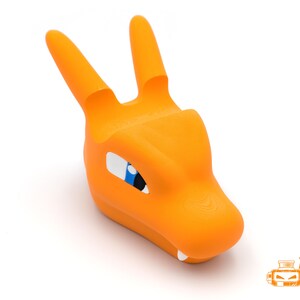 Op de afbeelding: Oranje 3D-geprinte Charizard telefoonhouder. De houder heeft de vorm van Charizards hoofd, met twee rechtopstaande hoorns, witte tanden en blauwe en witte ogen. Het product staat op een witte achtergrond. Het logo "Blaine's Geek Printz" staat rechtsonder.