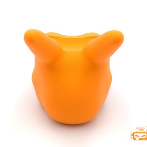 Op de afbeelding: Fel oranje 3D-geprint object met twee afgeronde uitsteeksels, die lijken op oren of handvatten, die omhoog steken. Het object heeft een gladde, matte afwerking en een afgeronde basis. De achtergrond is effen wit.
