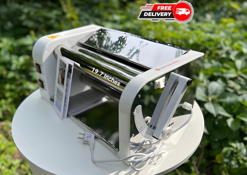 May include: A white electric dough sheeter with a polished metal roller measuring 19.7 inches in width. The machine features a side control panel with two switches, a white power cord with a plug, and an adjustable metal arm on the right side.