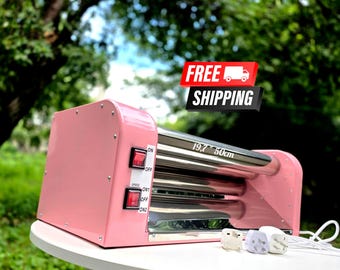 May include: A pink cup turner machine featuring two horizontal metallic rollers, a side control panel with two red power switches, and a white power cord with a plug. The device has a printed label indicating a length of 19.7 inches.