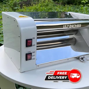 May include: A white electric dough roller machine with a polished stainless steel finish and two cylindrical rollers. The front panel features two red power switches labeled ON, OFF, SPEED, ON1, and ON2. The roller displays the text 15.7 INCHES.