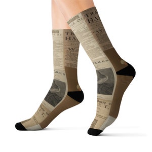 May include: A pair of socks with a vintage newspaper print design. The socks feature a brown and black color scheme with a repeating pattern of text and images. The text on the socks includes the words "The Die of" and "Trafalgar".
