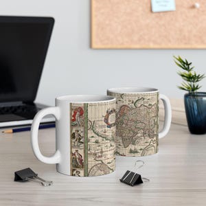 May include: Two white ceramic mugs featuring a vintage-style world map print. The design includes intricate cartographic details, historical illustrations of figures in the margins, and the Latin text Nova Totius Terrarum Orbis Geographica Tabula.