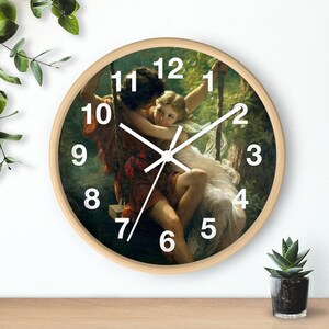 May include: A round wooden clock with a painting of a couple on a swing. The clock face has white Roman numerals and white hands.