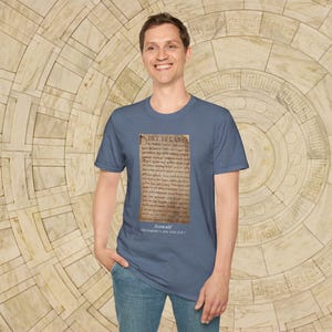 May include: A dark blue t-shirt with a faded image of an old manuscript page with the text "Hwæt! We Gardena in geardagum," which is the opening line of the epic poem Beowulf. The text below the image reads "Beowulf, Old English c. 700-1000 A.D."