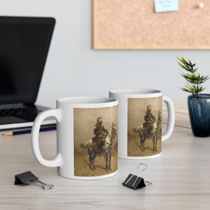 May include: Two white ceramic mugs featuring a printed historical painting of a soldier in a dark uniform riding a white horse. The artwork depicts a detailed scene with muted earth tones, showcasing the rider and horse in a classic equestrian pose.