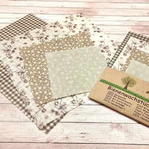 Könnte beinhalten: Set aus vier Bienenwachstüchern mit floralen Mustern in Braun- und Weißtönen. Die Tücher bestehen aus 100% Baumwolle, Bienenwachs, Jojobaöl und Baumharz. Die Verpackung ist aus braunem Papier und enthält den Text "Bienenwachstücher" und "made by Jarka".