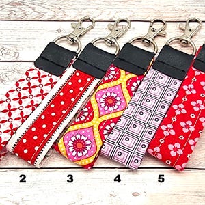 Può includere: Cinque portachiavi colorati con diversi motivi. I portachiavi sono rossi, rosa, gialli, bianchi e neri. Ogni portachiavi ha un anello portachiavi argentato.