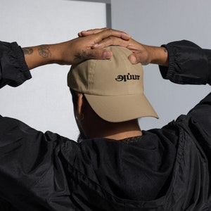 May include: A tan baseball cap with a black embroidered logo that says "auiuur".