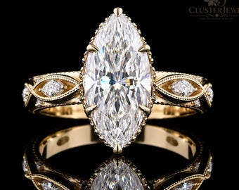 May include: A yellow gold ring featuring a large marquise-cut center stone held by six prongs. The band displays a detailed milgrain edge and is accented with smaller marquise-cut stones set within an intricate, woven-style metal framework.