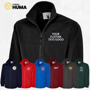 May include: A black fleece jacket with a zipper closure and a white embroidered text that says "YOUR CUSTOM TEXT/LOGO". The jacket is shown with six different color options: navy blue, red, blue, burgundy, gray, and green.