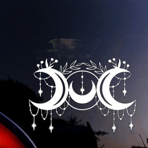 May include: White vinyl decal of a triple moon symbol with a floral design and dangling stars. The moon phases are crescent, full, and waning crescent.