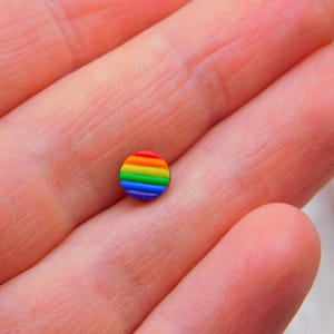Könnte beinhalten: Ein kleiner, runder Knopf in Regenbogenfarben mit schwarzem Rand.