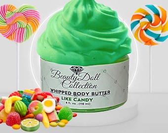 Pode incluir: Um pote de manteiga corporal batida verde com o rótulo "Beauty Doll Collection Whipped Body Butter Like Candy 4 fl. oz. (118 ml)". O pote está rodeado de doces coloridos.