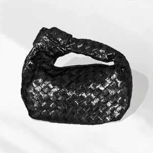 May include: A black woven leather handbag with a knotted handle.