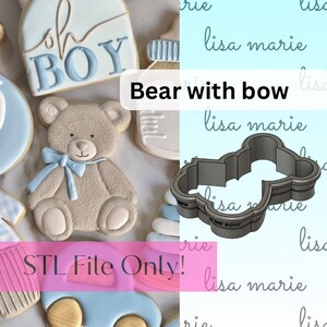May include: A 3D printed cookie cutter in the shape of a bear with a bow. The cutter is made of gray plastic and has a smooth finish. The cutter is designed to cut out cookies in the shape of a bear with a bow.