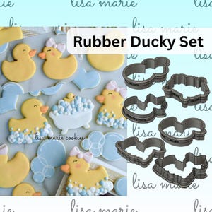 May include: A collection of yellow rubber ducky-themed cookies with blue and white accents, alongside matching cookie cutters. The cookies feature duck shapes, a bathtub, and bow details. The text "Rubber Ducky Set" is visible.