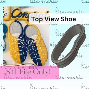 May include: A 3D printed cookie cutter in the shape of a shoe, viewed from above. The cutter is grey and has a smooth, rounded surface. The text "Top View Shoe" is written in white letters on a blue background.