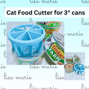 May include: A light blue plastic cat food cutter designed for 3-inch cans. The tool features a circular frame with eight radial blades that divide food into equal portions. The text "Cat Food Cutter for 3" cans" is visible at the top of the image.
