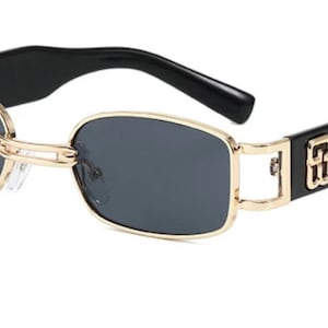 May include: Black rectangular sunglasses with gold metal frames and black arms. The arms have a gold logo.