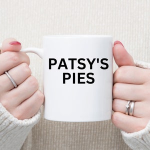 May include: White ceramic mug with black text that reads "PATSY'S PIES".