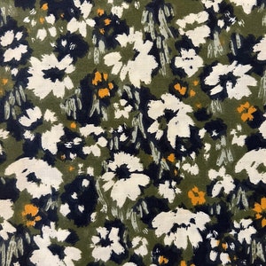 Könnte beinhalten: Nahaufnahme eines Stoffes mit floralem Muster. Das Design zeigt weiße, marineblaue und gelbe Blumen, die auf einem olivgrünen Hintergrund verstreut sind. Die Blumen haben einen Pinselstrich-Stil, der ein strukturiertes Aussehen erzeugt.