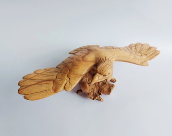 Puede incluir: Una talla de madera de un halcón o águila con las alas extendidas, posado en una rama de árbol. La talla es detallada y realista, con plumas y garras visibles.