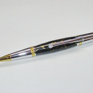 May include: A luxury pen with a black and gold marbled barrel, silver accents, and a gold-colored tip. The pen features a small diamond-like embellishment and gold-colored bands. The pen is designed for writing.