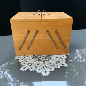 May include: A wooden box with two compartments and a hinged lid. The box has brass hinges and clasps. The box is sitting on a white lace doily.